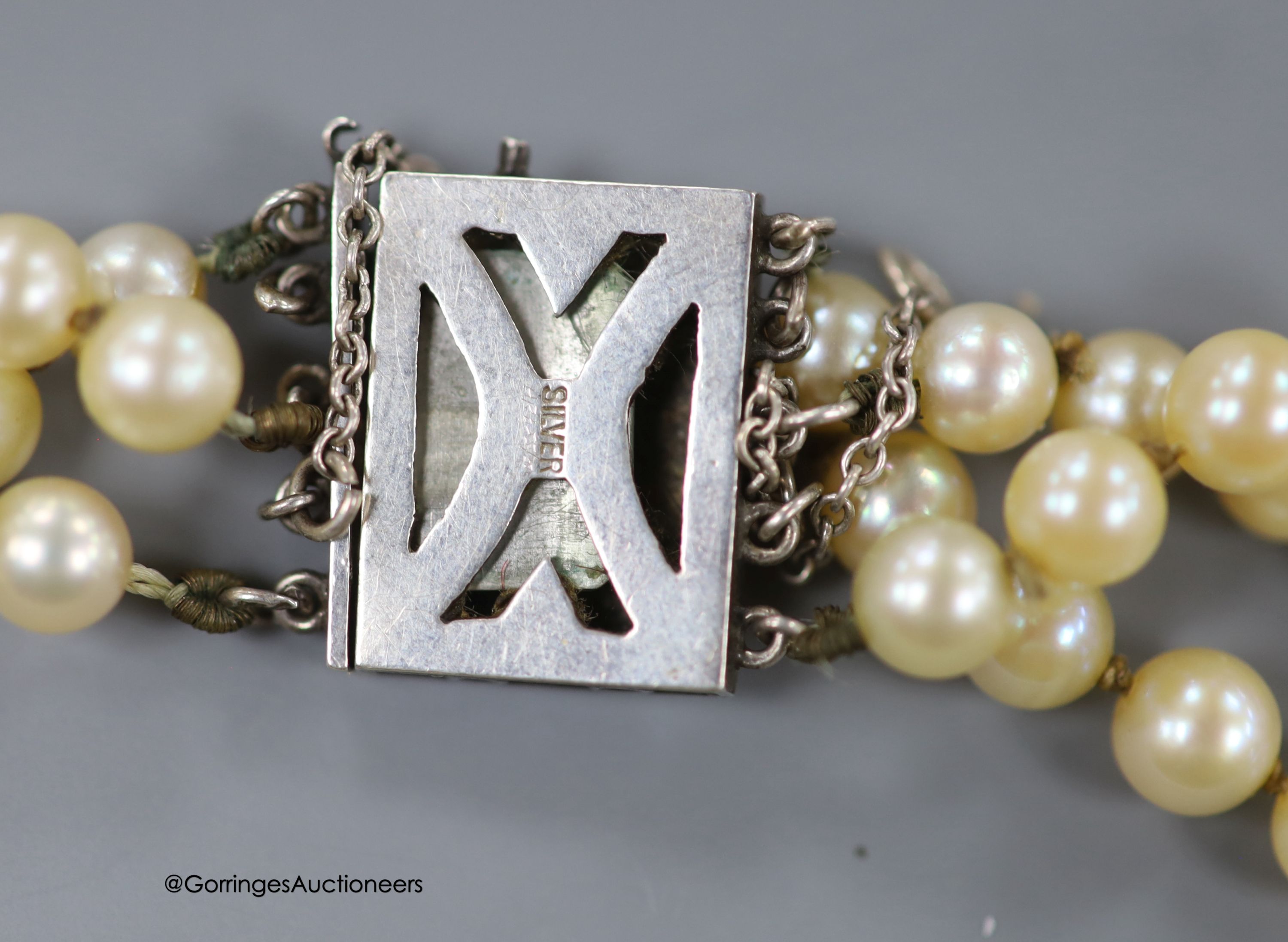 A triple strand cultured pearl choker necklace with white metal clasp, stamped 'silver', 41cm.